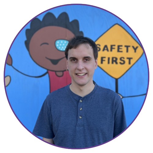 A young man posing for a photo with s decorative wall behind him that says "safety first."