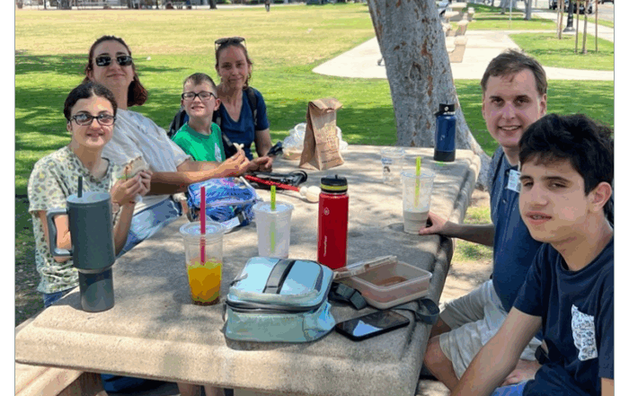 A group enjoys a picnic lunch at a park table.