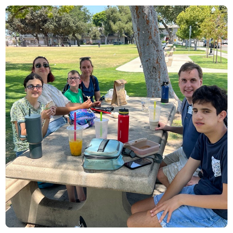 A group enjoys a picnic lunch at a park table.