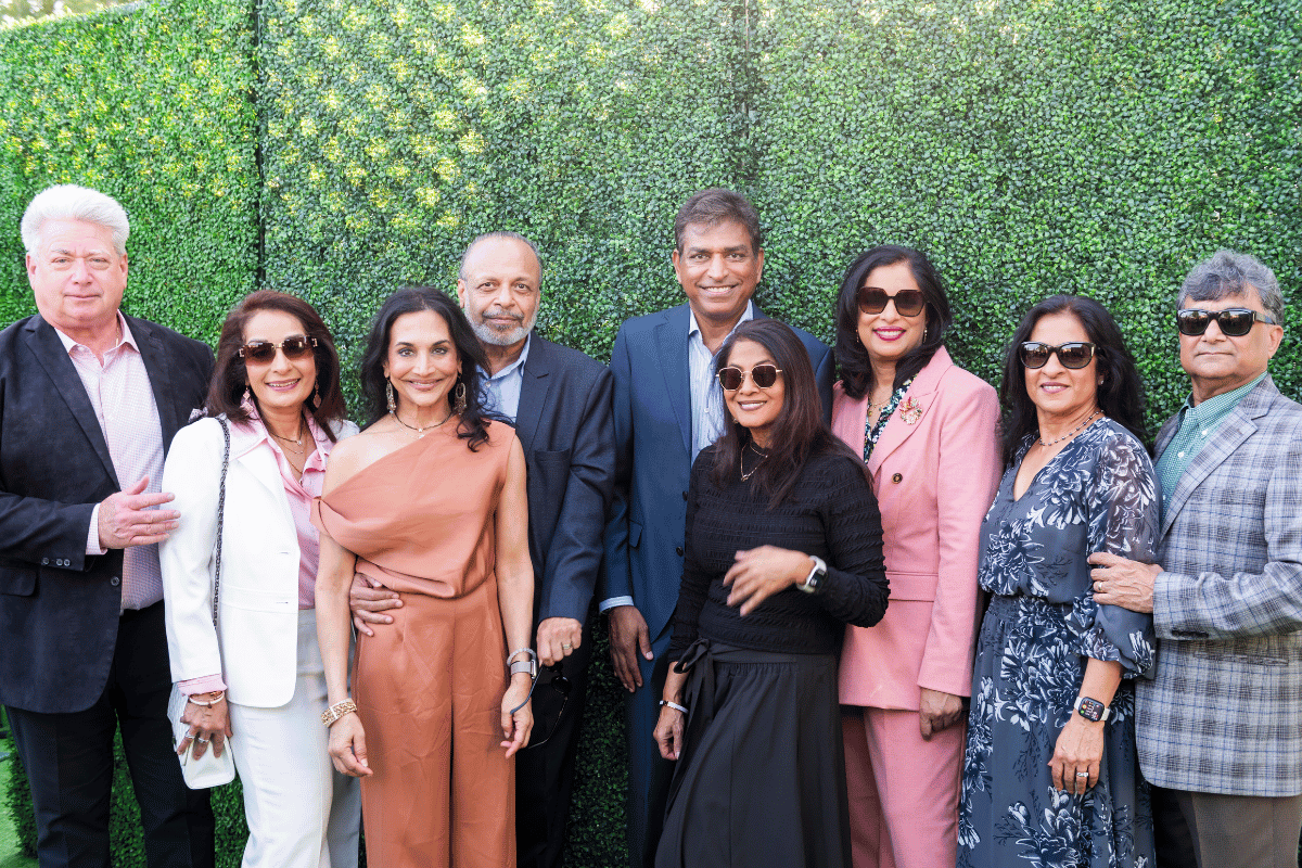 Large group stands in front of greenery