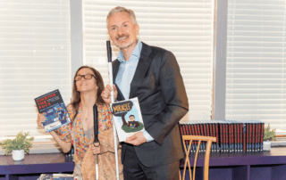 A man and woman pose holding books