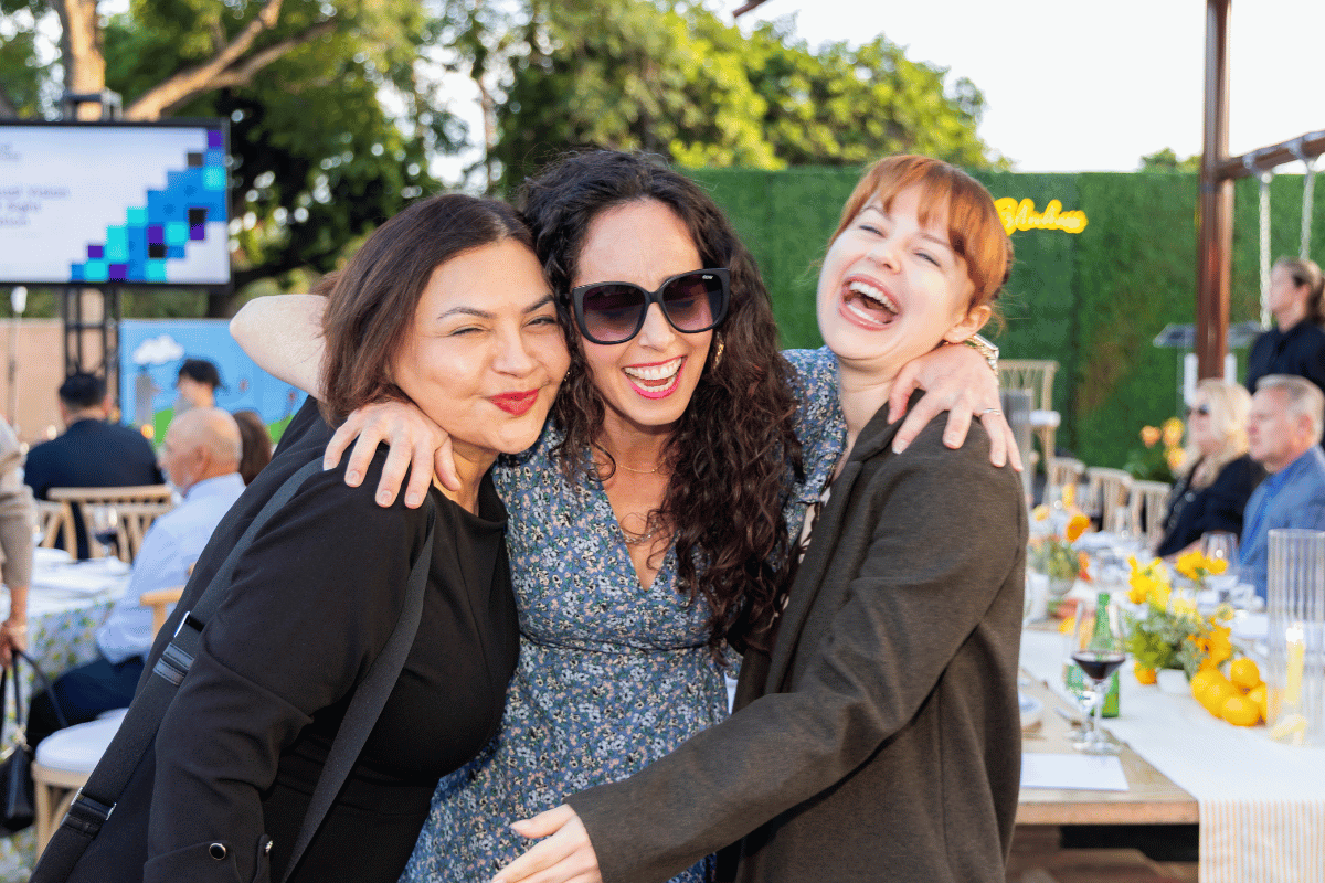 Three women smiling in front of a table