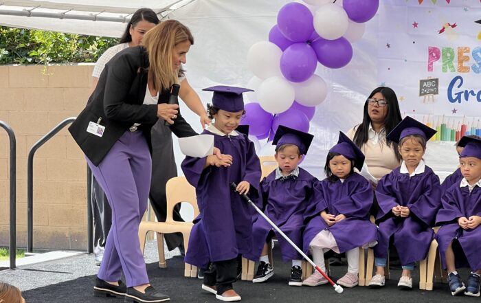 Children on stage in caps and gowns
